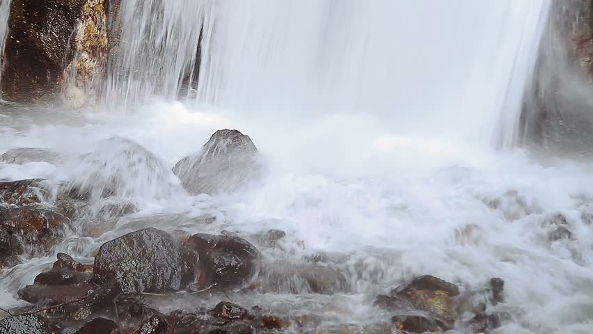 Forest waterfall detail, water splashing while falling over rocks 