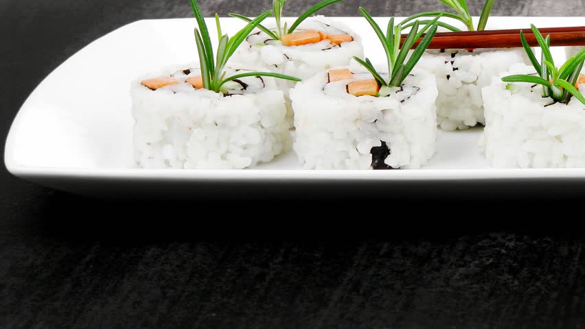 Japanese Cuisine - California Roll made of Salmon Cream Cheese and Avocado inside. Served with wasabi and ginger . on long white plate over black table 1920x1080 intro motion slow hidef hd