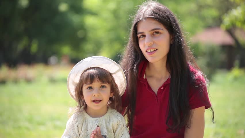 Young adult mother and daughter sing and hug together.
