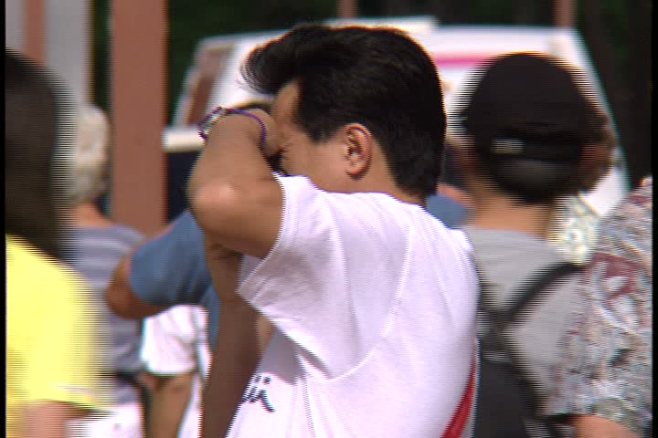 WAIKIKI BEACH, HONOLULU, HAWAII - JANUARY 30, 1997: MS mass of tourists walking through frame. One man stops in crowd to take a photograph.