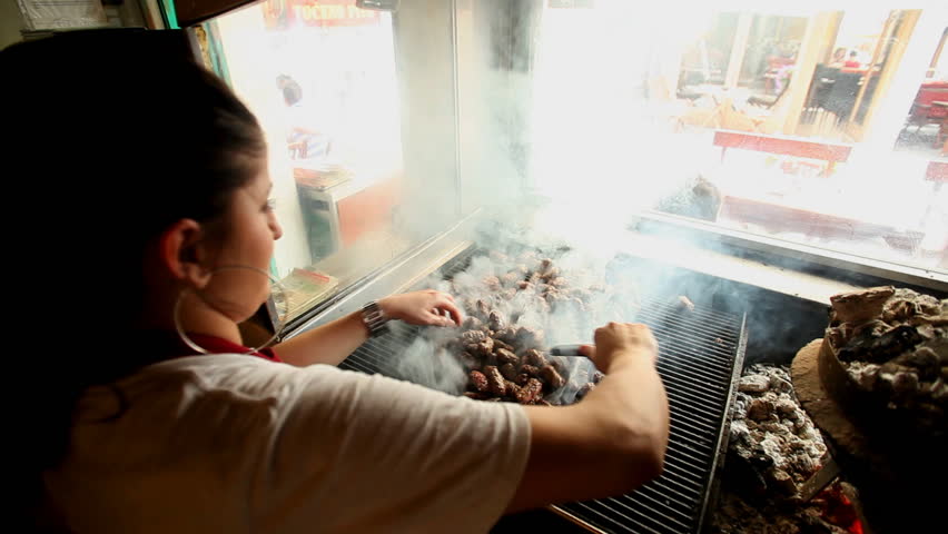 SARAJEVO, BOSNIA - AUGUST 13: Woman grilling cevapci on grill in restaurant on August 13, 2012 in Sarajevo, Bosnia. The Sarajevan Cevapi meat is famous throughout the Balkan region.