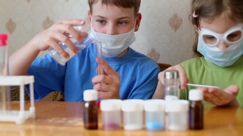 Boy and girl sit at table and make chemical experiments