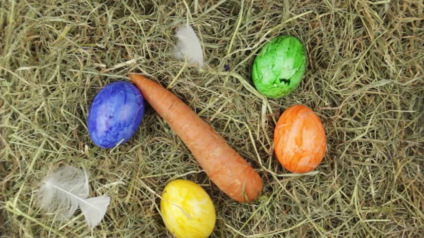 A hand collects a few easter eggs from a pile of straw