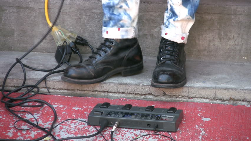 Rockabilly guitarist taps his black boots to the rhythm.