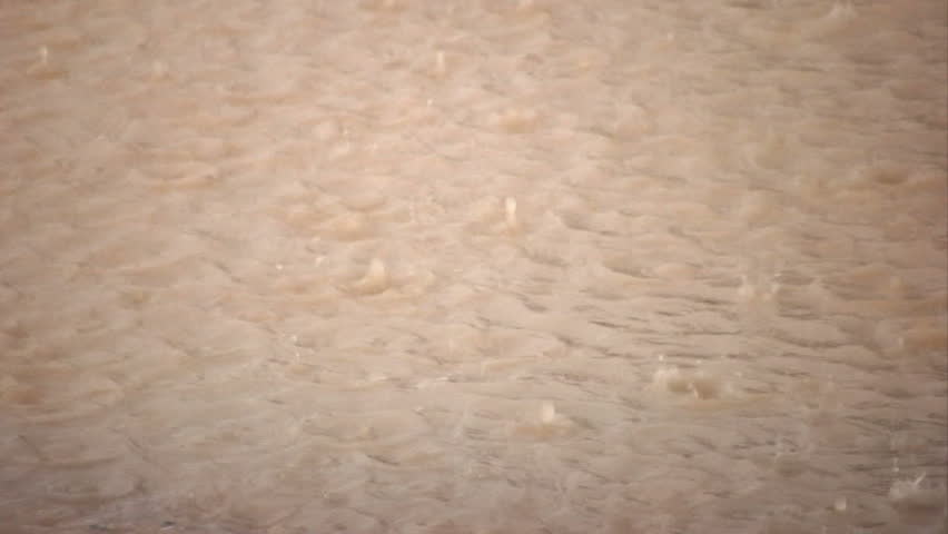 Raindrops splashing into a muddy puddle.