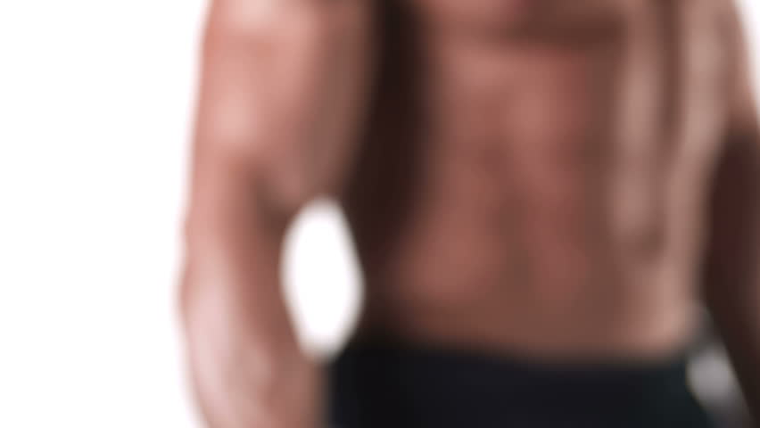 Close up shot of a muscular bodybuilder doing dumbbell curls with his large bicep muscles on a white background, with a camera pan, and rack focus