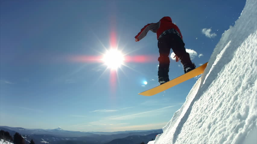Snowboarder jumps off snow cliff, slow motion