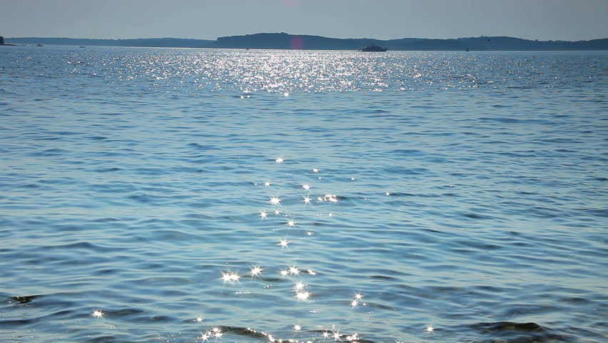 Sparks on the sea wave and boat on the horizon