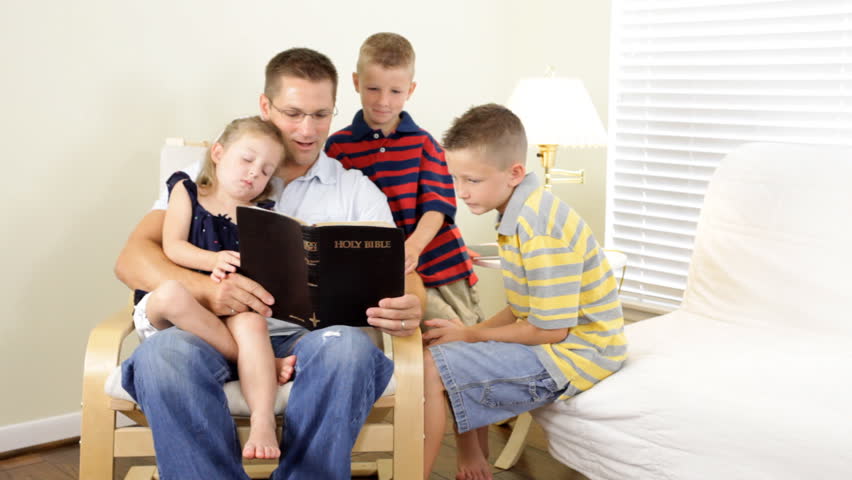 A father reads to his children from the Holy Bible.