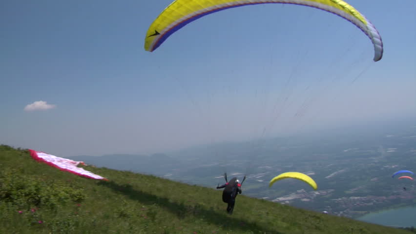 Paraglider launching from the ridge with an colorful canopy against a blue sky.