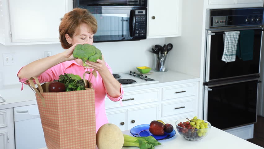 A happy couple enjoying conversation, and the fresh fruits and vegetables the woman has just purchased.
