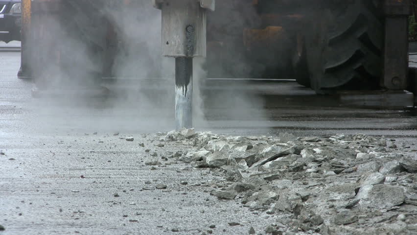 A heavy duty jackhammer begins to bust up the concrete to repair a road in Bangkok, Thailand.