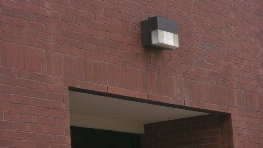 Zooming out from the rear entrance of a red bricked public school, revealing an empty concrete school yard.