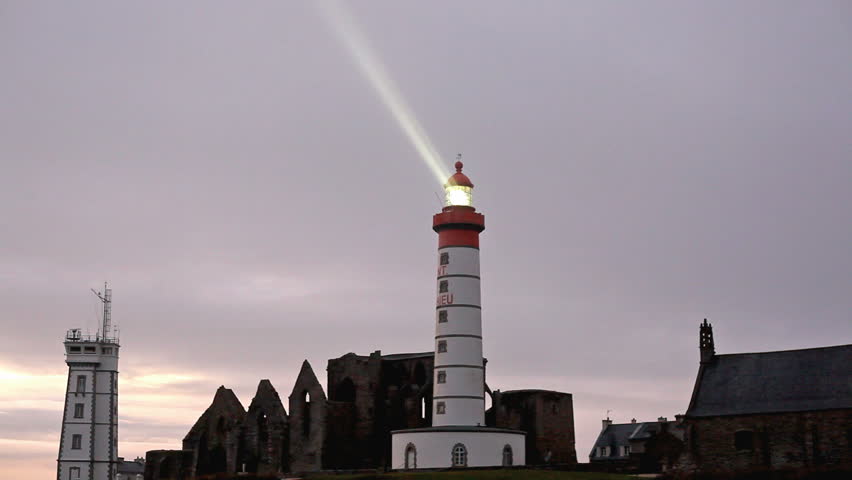 Saint Mathieu lighthouse lighted at sunset and abbey ruins, brittany, france.