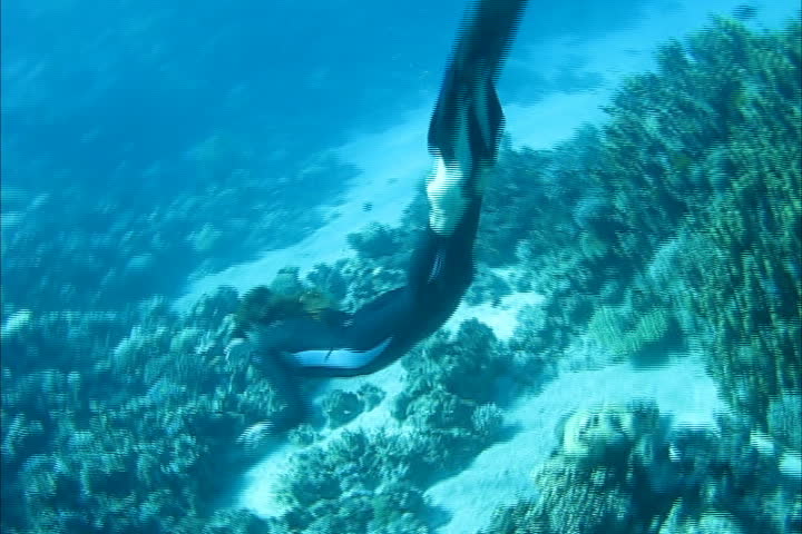 Beautiful freediver girl swims along coral reef near the sand bottom of the Red Sea