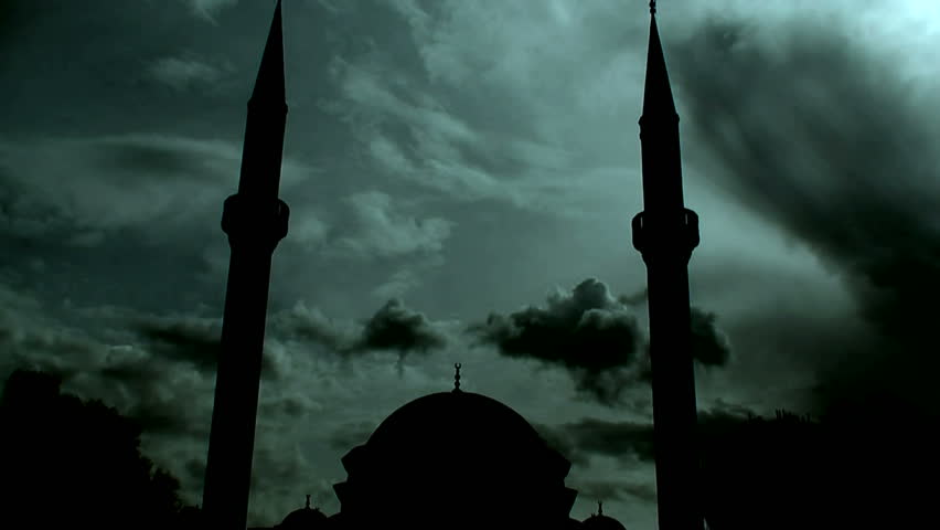Time lapse clouds flowing past silhouetted twin minaret mosque 3