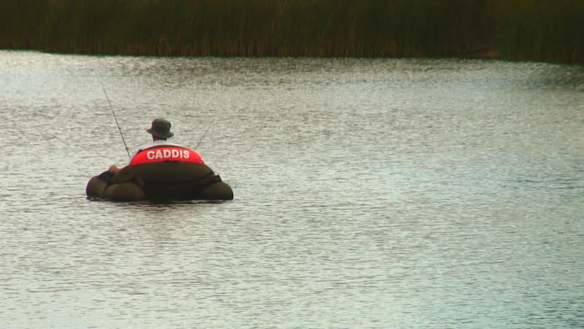 man fishes from float tube on small lake