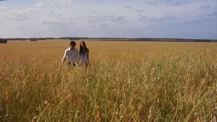 Happy couple walking along wheat field