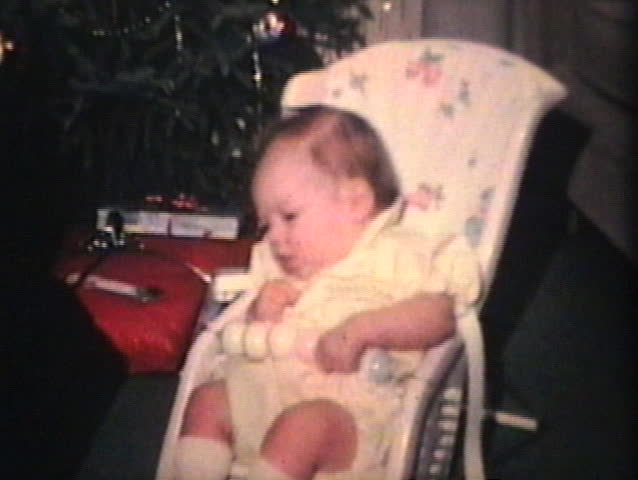 A proud big brother gives his new baby sister a Christmas gift and a kiss. (Vintage 8mm film)