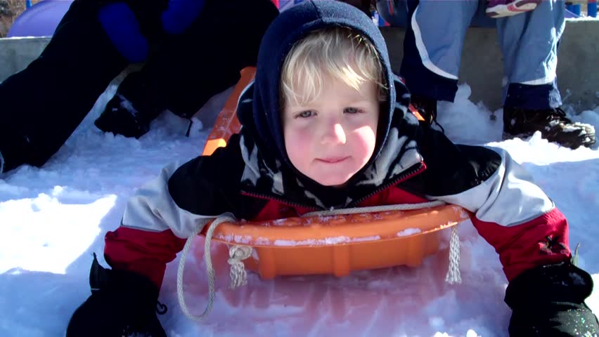 action clip of cute little boy riding down a steep hill on a toboggan