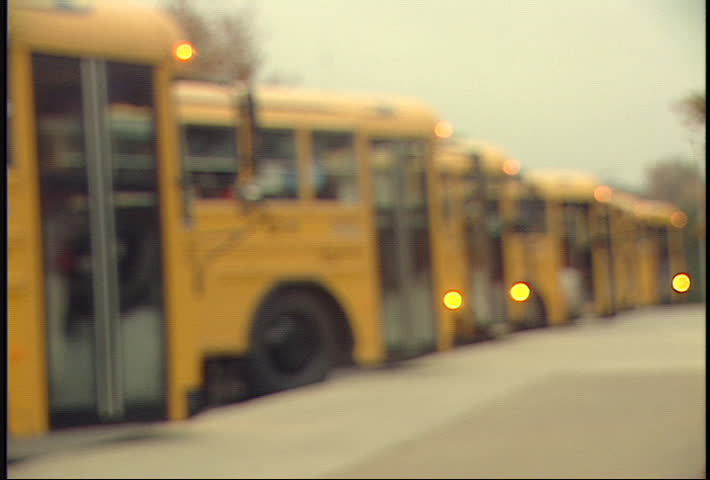 Rack focus of school buses waiting to drop off kids