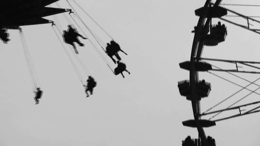 Swings and ferris wheel in silhouette. Sunset at fairground. Black and white. 2 shots.