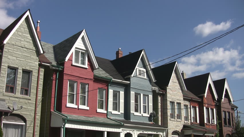 Row of Victorian houses in a Toronto neighborhood. Light timelapse clouds move overhead. 