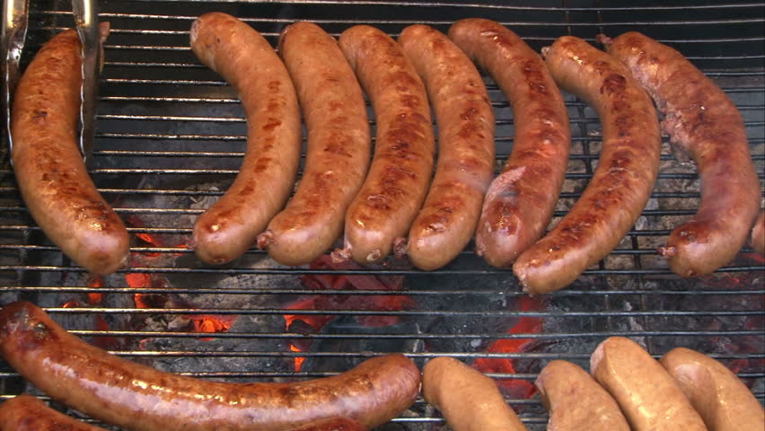 Bratwurst on the grill. Working with sausages on the grill.