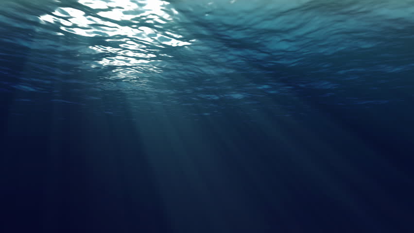 An underwater looped scene with sun rays shining through the water's glittering and moving surface. Use as background.