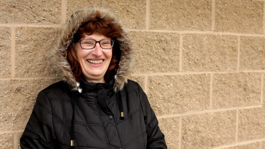 Elderly Woman laughing in front of brick wall