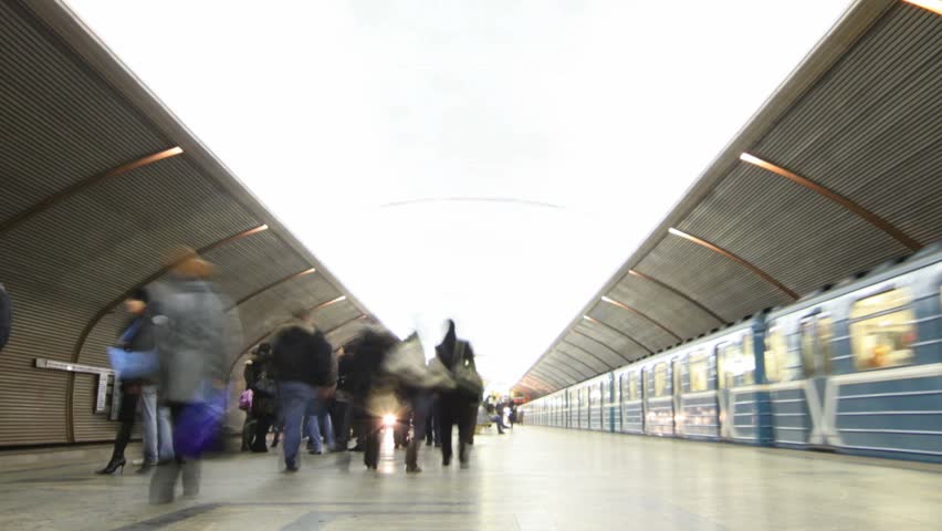 People on platform on station of subway, two trains arrive and leave. Camera keeps away. Time lapse. 