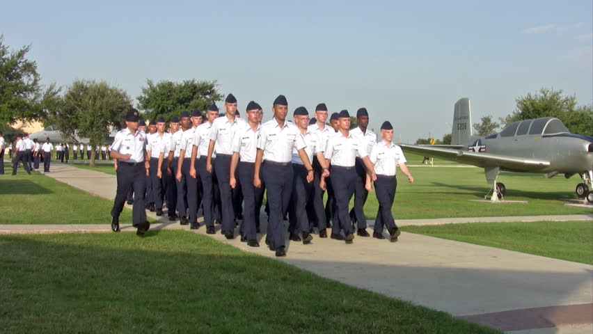 Video of USAF enlisted Basic Training graduates marching onto parade field for ceremony. Blue uniform with Drill Sergeants barking commands. Family watching. Lackland AFB San Antonio, Texas. 