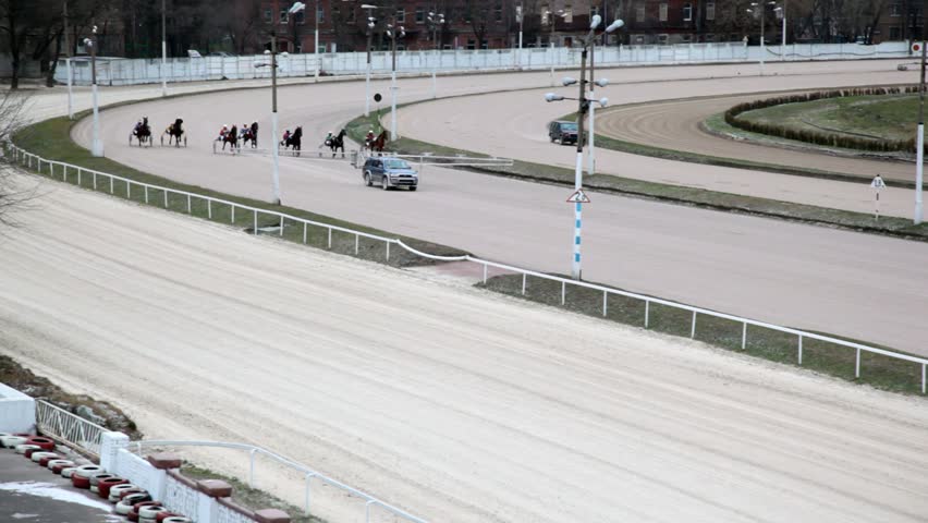 review of horses with equestrians competing on hippodrome track before an escort car 