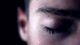 Closeup of young male eye against dark background