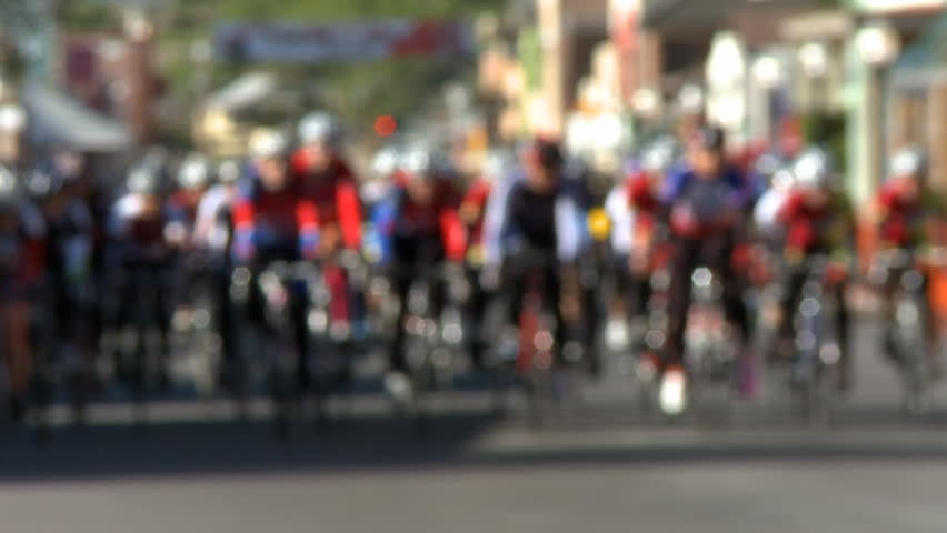 A group of stage race cyclists make a turn. Slow motion, defocused.