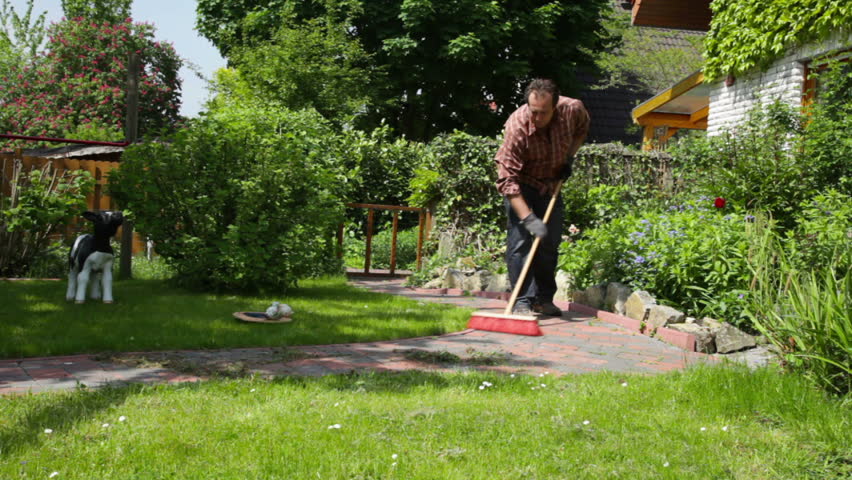 man sweeping the garden path at home
