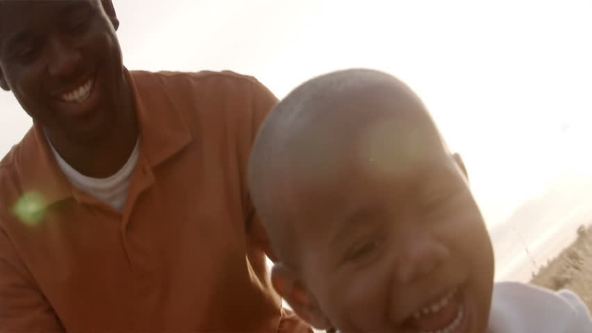 A father and son play in a wheat field on a sunny day.