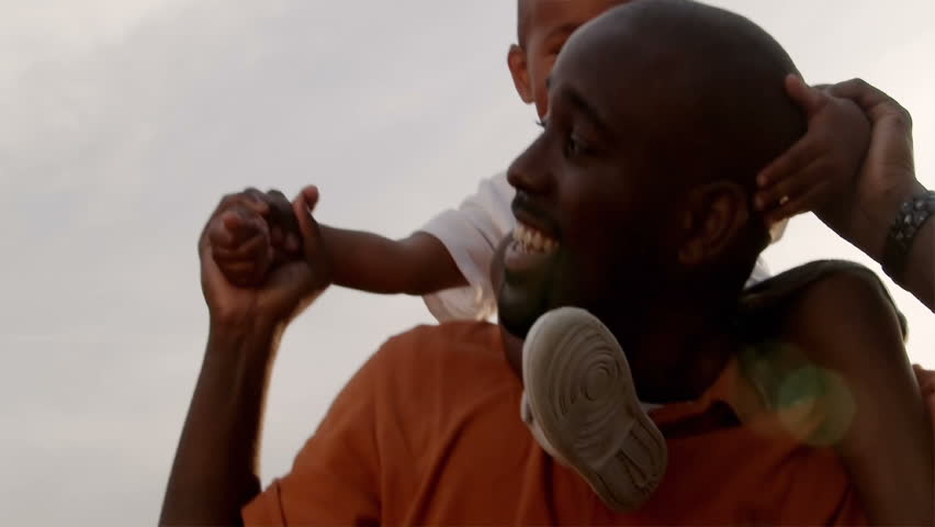 A father and son play in a wheat field on a sunny day.
