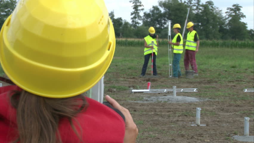 Geodesist with workers are adjusting pillar in cement for solar power plant construction.