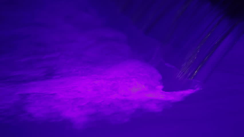 Violet light waterfall. A small waterfall and a torrent of water. Violet light water.
