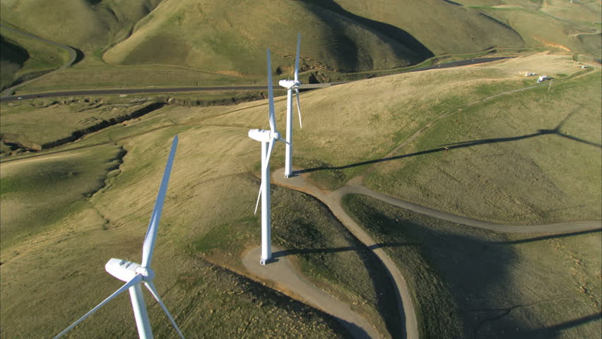 Low aerial view of cluster of wind turbines in green hillside