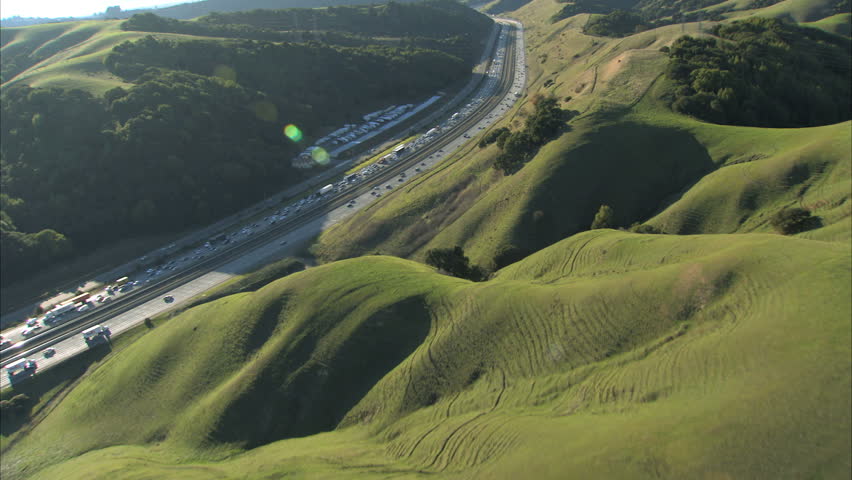 Aerial view of heavy  traffic using  busy freeway in the hills outside a city