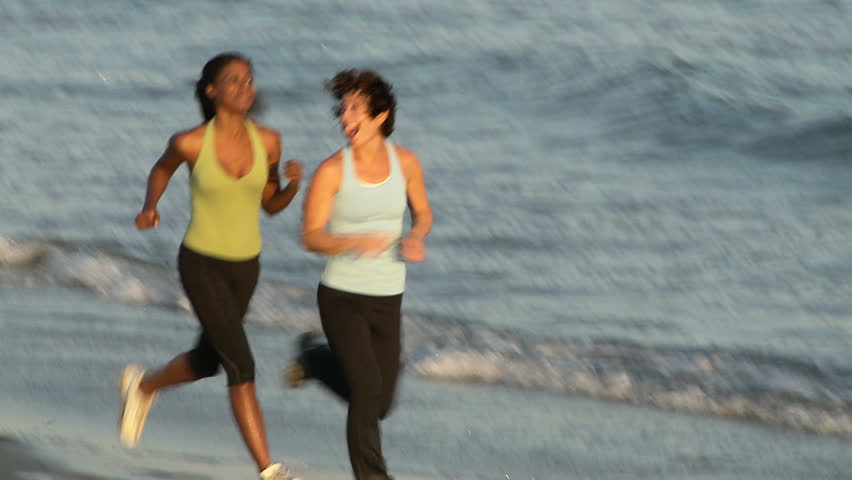 young women running along shore line at s