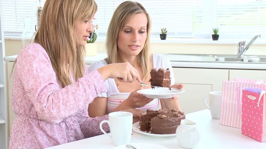 Jolly young women eating chocolate cake in the kitchen