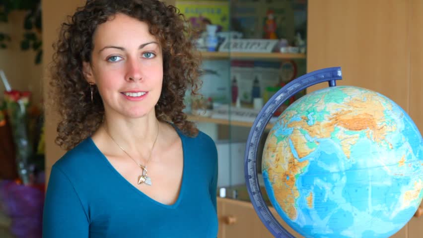 beautiful schoolteacher selecting continents and countries on globe