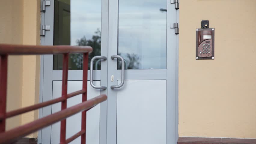 little girl uses entrance door intercom of apartment building