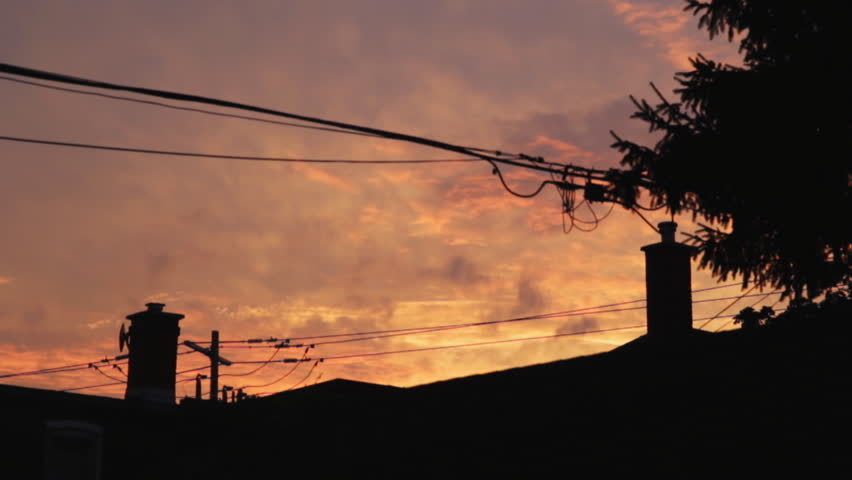 Suburban sunset. Timelapse. Colourful timelapse clouds move over suburban rooftops and wires.  