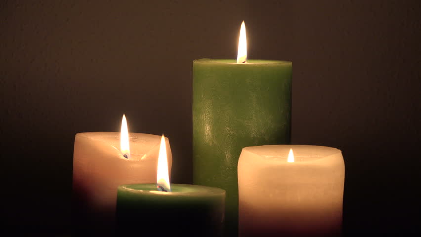 Dolly Shot Of White Candles Burning With Soft Candle Light On Black