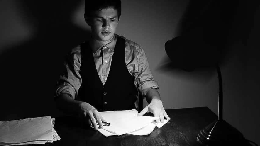 A young man frantically trying to do an overwhelming amount of paper work. Black and white HD 720p footage.