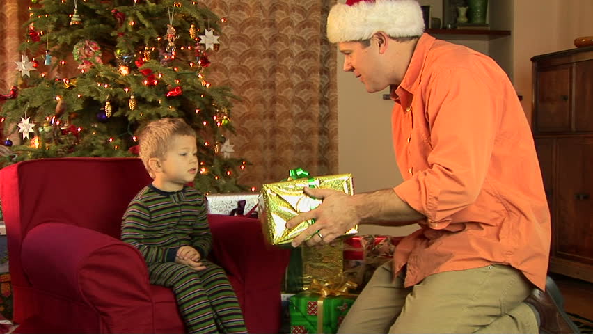Father and little boy in pajamas opening Christmas present 